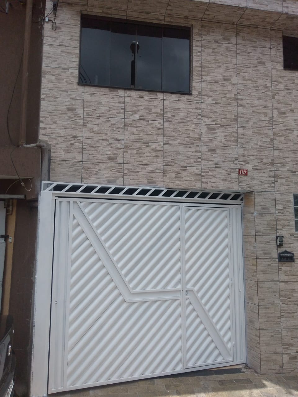 Portão metálico branco instalado em fachada residencial